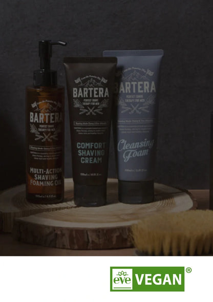 Bartera grooming products including a pump bottle, tube of cream, and tube of cleansing foam on a wooden block with a dark background.
