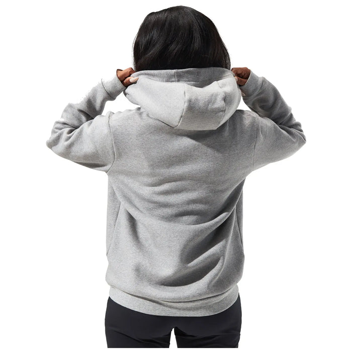 A person is adjusting the hood of a gray sweatshirt while facing away. The background is plain white, emphasizing the action and the clothing.