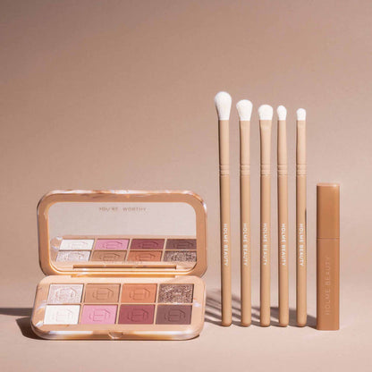 Makeup palette, brushes, and a tube on a beige background