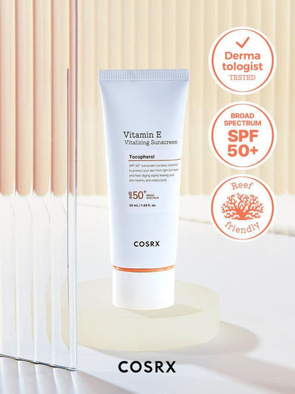 Clinically proven COSRX Vitamin E Vitalizing Sunscreen SPF 50+ in studio setting with Reef Friendly and Broad Spectrum badges; Korean UV protection formula rich in vitamin E to hydrate and brighten skin tone while remaining transparent on all skin types for daily use under makeup.