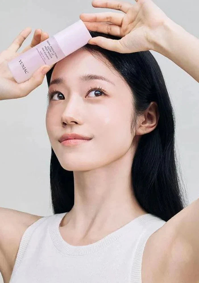 Woman applying a pink skincare product to her face with a neutral background